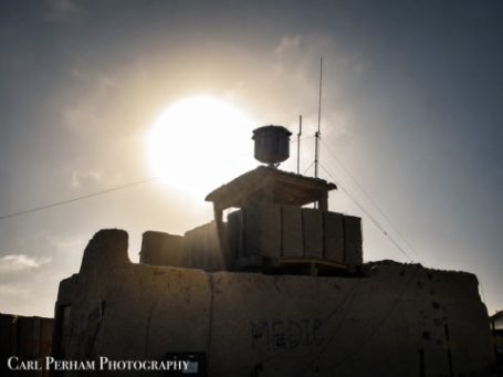 Silhouette of a tower against a bright sun in a clear sky.