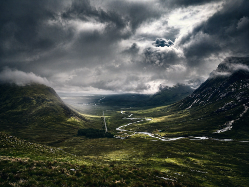 Scottish Highlands Dramatic valley landscape with mountains, clouds, and a winding river.