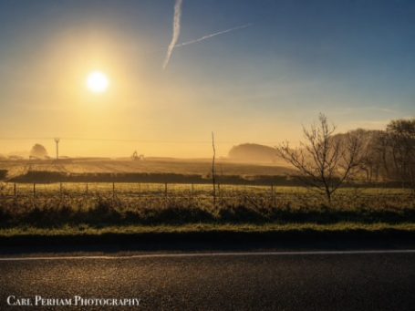 Misty Sunrise - Barnstaple Sunrise over a misty landscape with fields and distant hills under a clear sky.