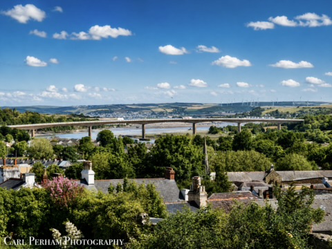 Bideford View of a river and bridge surrounded by greenery and blue sky with clouds.