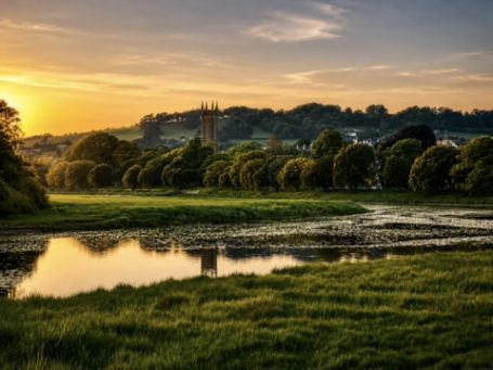 Sunset over a tranquil landscape with trees and a reflective river.