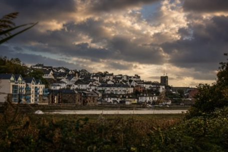View of a coastal town with white buildings under a dramatic cloudy sky.