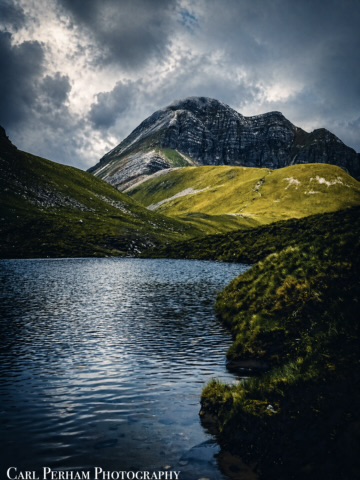 Fort William Camping A scenic mountain landscape with a serene lake and dramatic clouds.