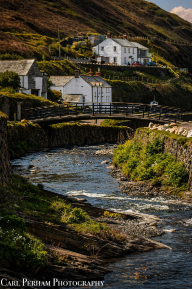Cottages on a hillside beside a winding river in a scenic landscape.